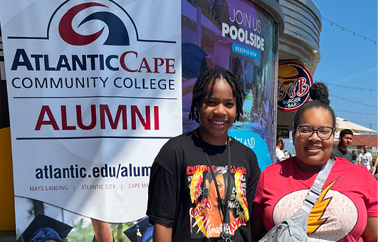 two alumni next to alumni sign