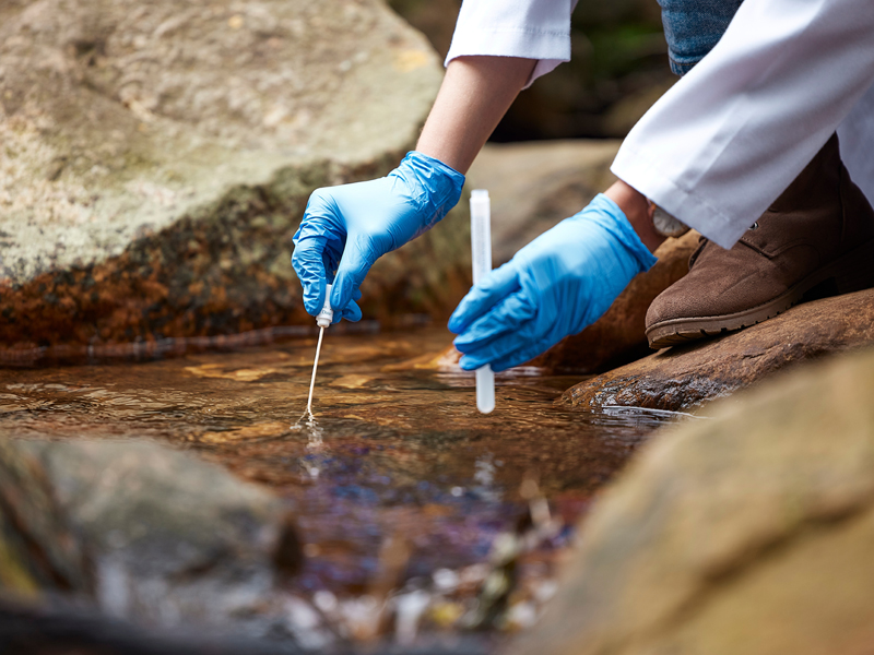science student with test tube in a creek