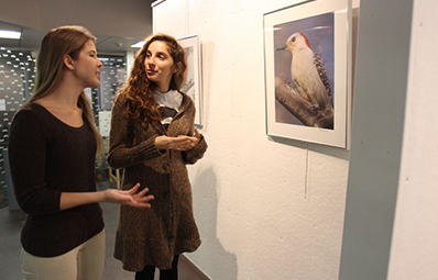art student talking about her painting person in the art gallery.