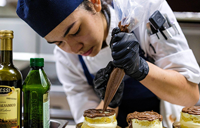 culinary student putting icing on a cake.