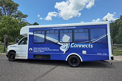 SJ Connects shuttle bus parked along a tree-lined road.