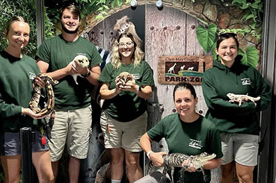 Five Cape May County Park and Zoo staff members pose with ambassador animals, including a snake, ferrets and an alligator.