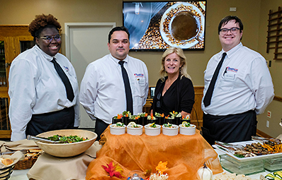 Culinary students posing in front of meals laid out for display.