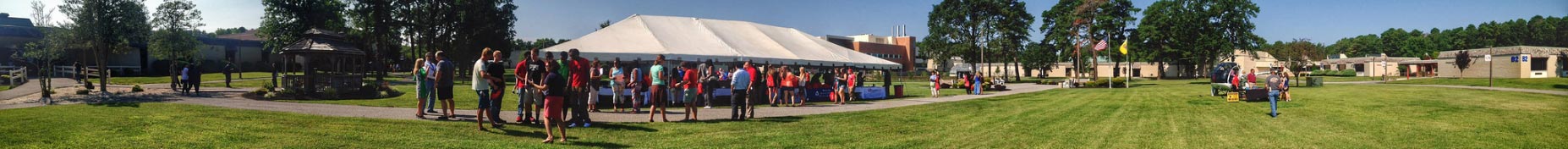 students under white tent at campus event