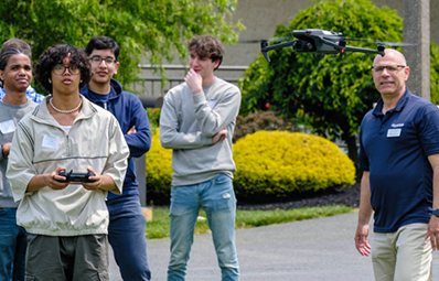 Instructor and students flying a drone on campus