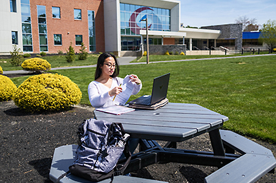 Student sitting at a bench in the Mays Landing campus quad.