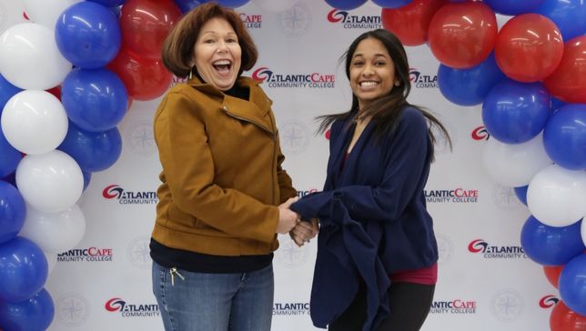 teacher and student jumping in front of a balloon arch