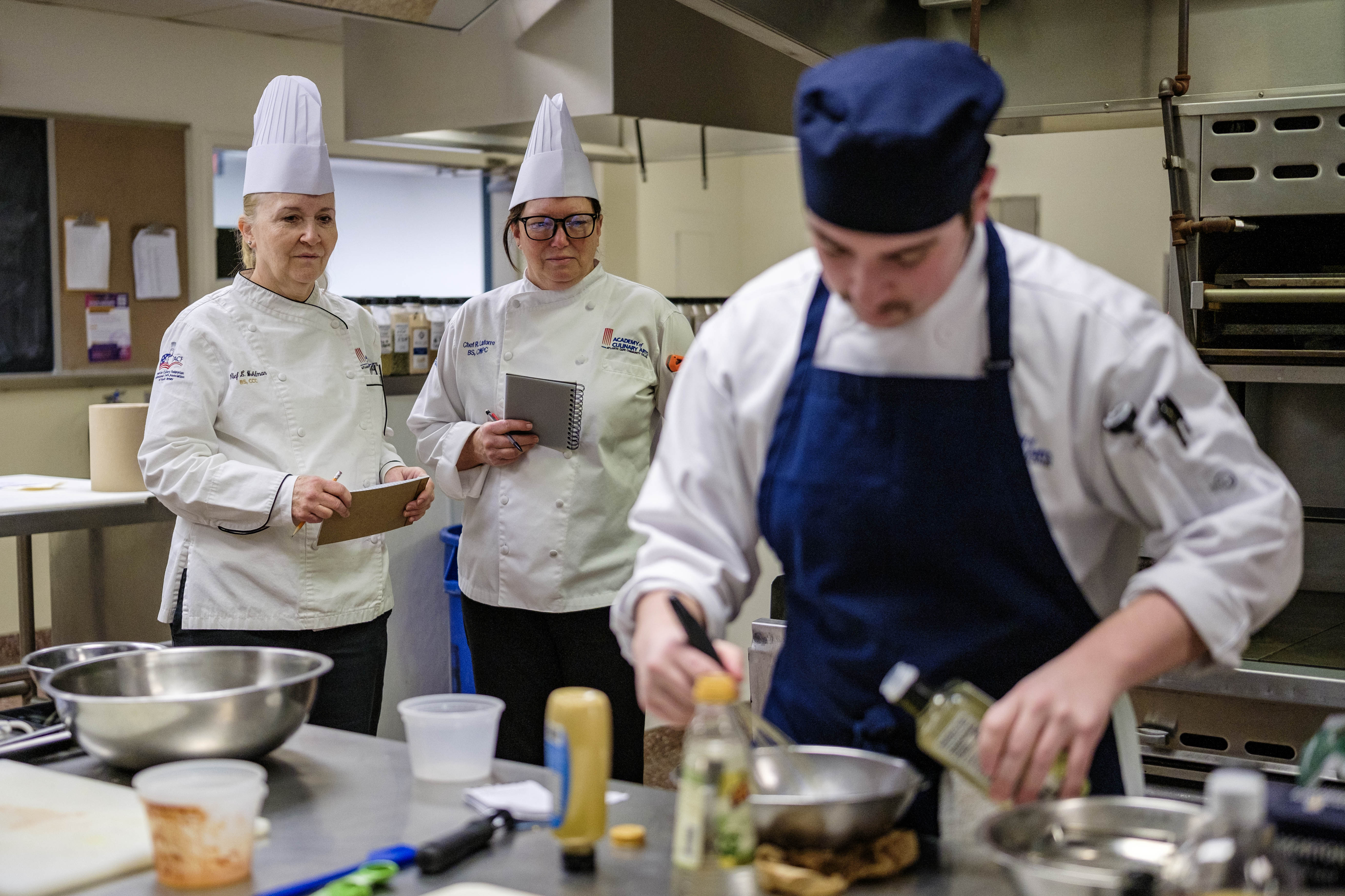 ACA chef educators observing a student cook wings