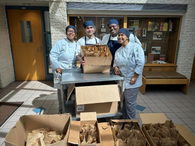 Amy and Danna help create food boxes for Angels in Motion with classmates