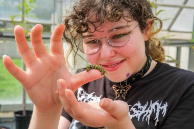 An Atlantic Cape student admires a caterpillar