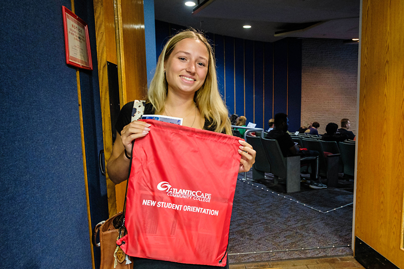 Student at new student orientation holding up a goodie bag.
