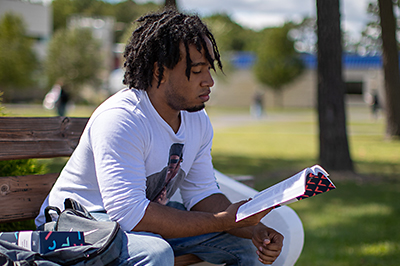 Student in the quad at Mays Landing campus studying.
