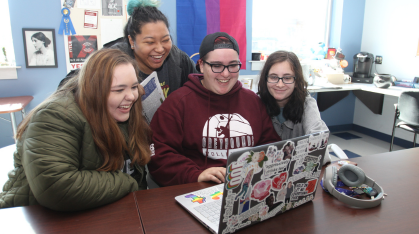students laughing around a computer
