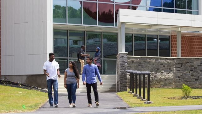 three students walling by G building