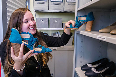 Campus closet student worker stocking the shoe shelf.