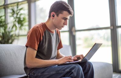 student on his computer with earbuds on