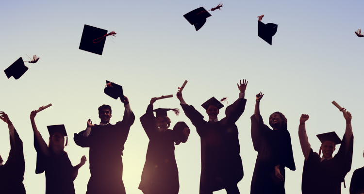 college students throwing graduation caps in the air