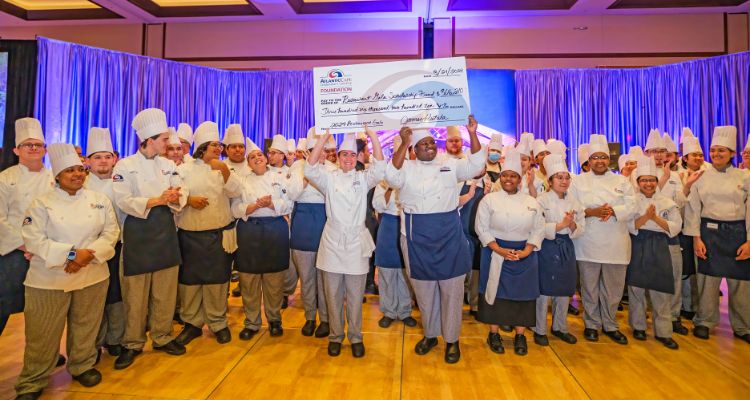 Students from the Academy of Culinary Arts display the scholarship funds raised check