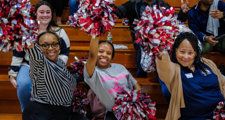 Staff members shake pom poms to get into the spirit