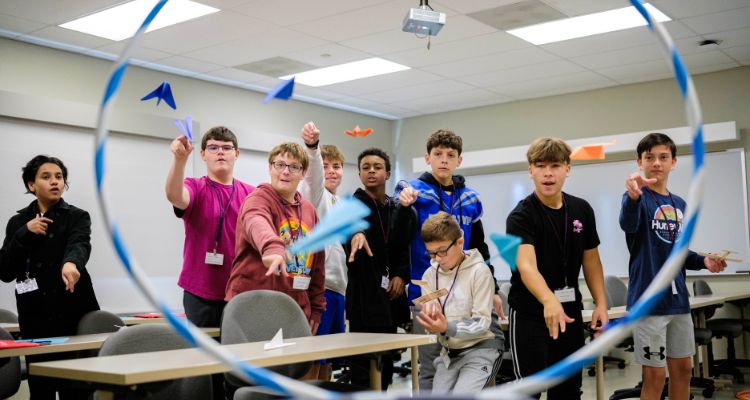 Students demonstrate proper flight techniques with paper airplanes