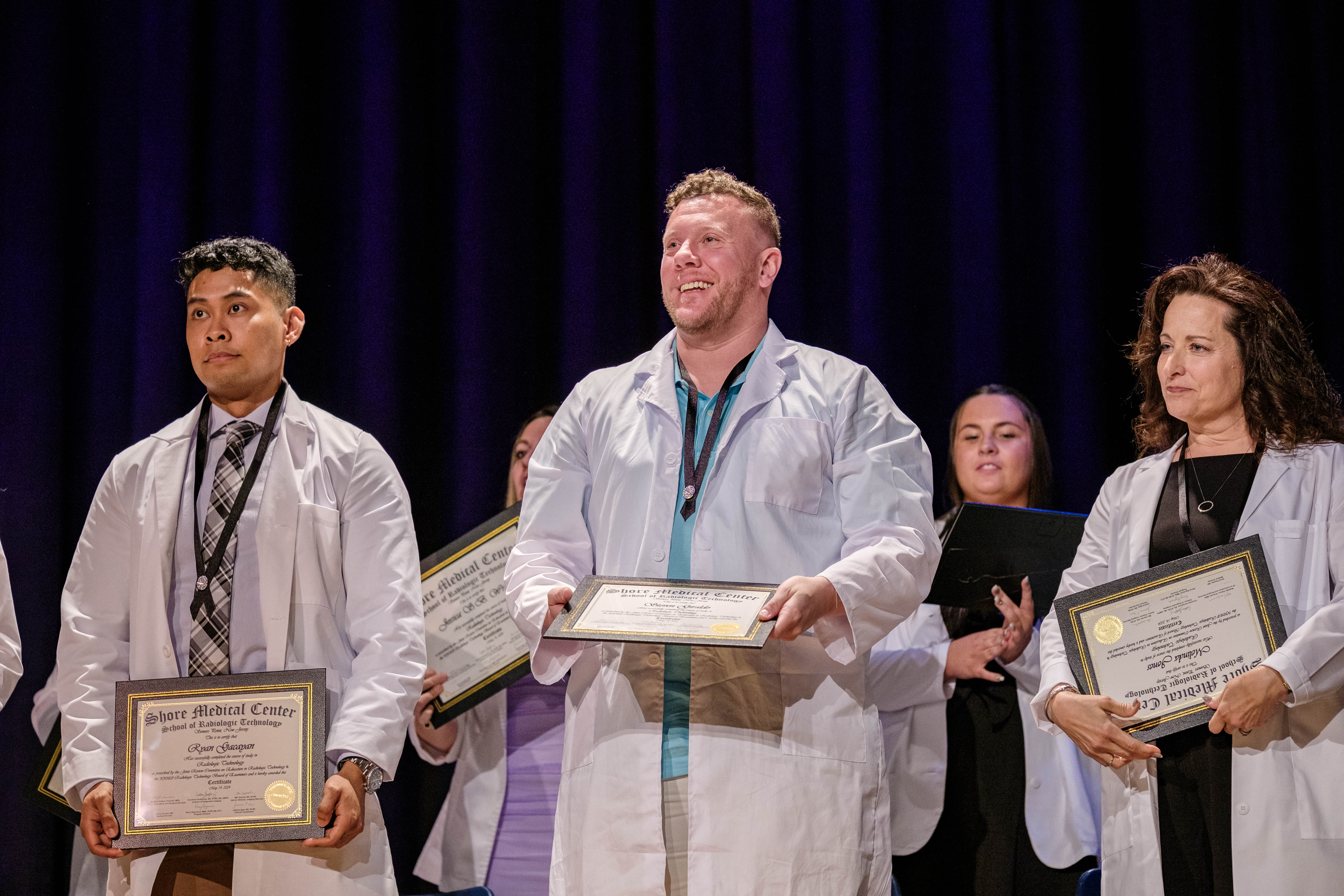 Graduate on stage smiles at the audience