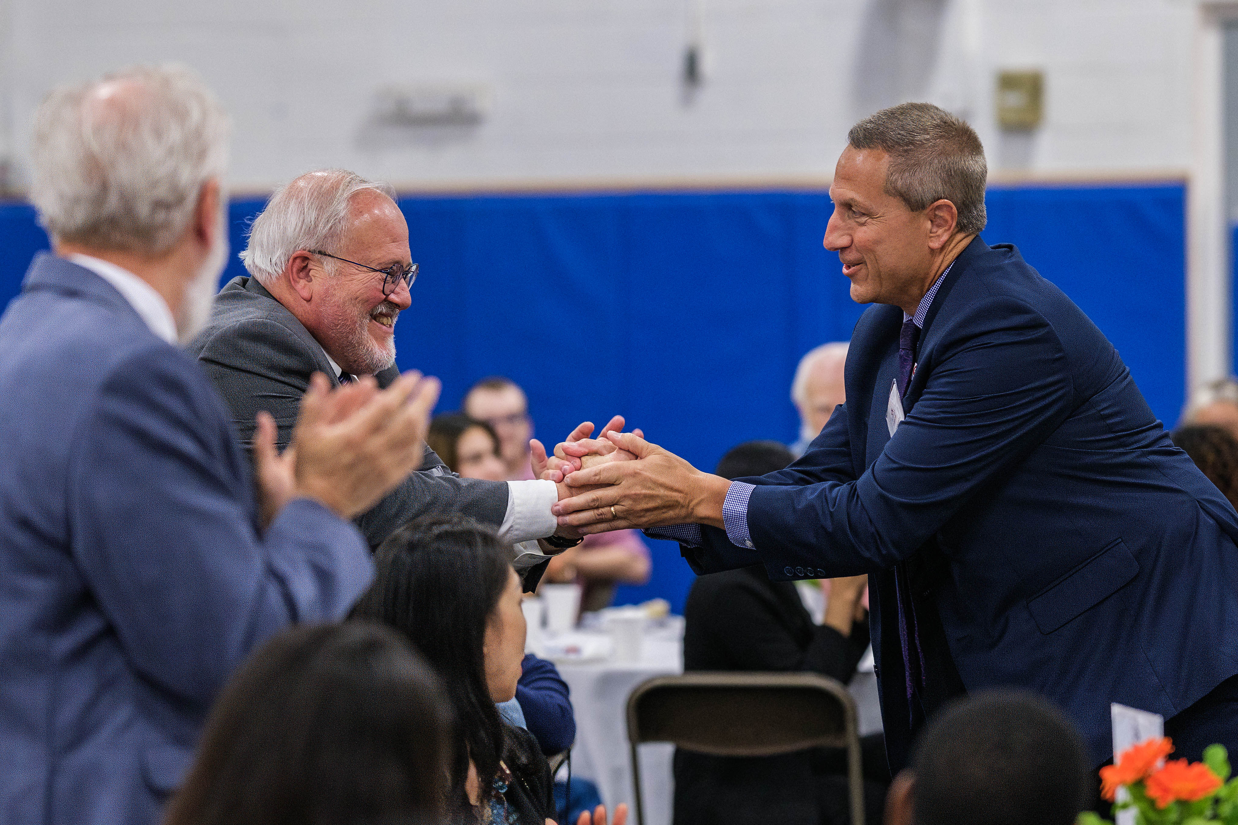 Donor Vincent D'Alessandro on the right shakes hands with another donor